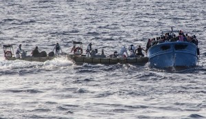 In this photo taken on July 2, 2013 and made available by the Italian Navy Wednesday, July 3, 2013, Coast Guard boats give help to a boat with some 80 migrants on a boat heading to Italy, in the Mediterranean sea, near the island of Lampedusa. The Vatican announced Monday that Pope Francis will go to Lampedusa island next week to meet with recently arrived migrants. Tens of thousands of clandestine migrants, many from Africa or the Mideast, head to Italian shores each year. Lampedusa is their frequent destination, closer to Africa than the Italian mainland. (AP Photo/Italian Navy, HO)